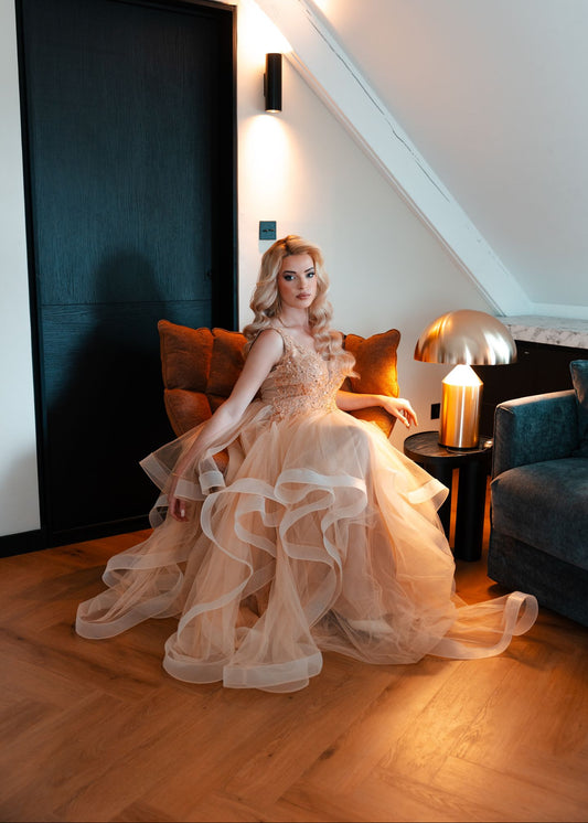 La mannequin pose dans une suite de l'Hotel La Cloche à Dijon. Elle porte une somptueuse robe de soirée doté de nombreux volants en tulle et d'un haut très travaillé.